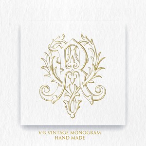 Puede incluir: Un monograma vintage dorado con las letras "R" y "A" entrelazadas, rodeado de diseños florales ornamentados. El texto "V-R VINTAGE MONOGRAM HAND MADE" está debajo del monograma.