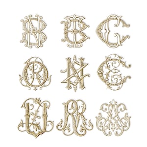 May include: Nine ornate, gold-colored monogram designs are displayed against a white background. Each monogram features elegant, swirling lines and decorative flourishes, with letters such as B, C, G, R, N, J, and K. The designs are likely for personalization.