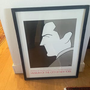 May include: A framed print featuring a stylized black and white profile illustration of a person. The text at the bottom reads: DRAWINGS BY WILLIAM AUERBACH-LEVY THEATRE COLLECTION MUSEUM OF THE CITY OF NEW YORK. The frame is thin and black.