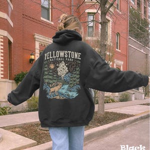 May include: Black hoodie with a graphic print of a forest scene and a deer. The text "Yellowstone National Park" is printed on the hoodie.