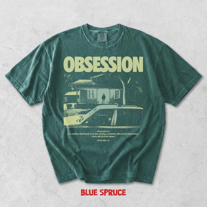 May include: A dark green short-sleeve t-shirt featuring the word OBSESSION in large letters above a graphic of a house and a car. Below the graphic, the text reads: obsession (n) 1. A relentless attachment to an idea, feeling, or emotion.