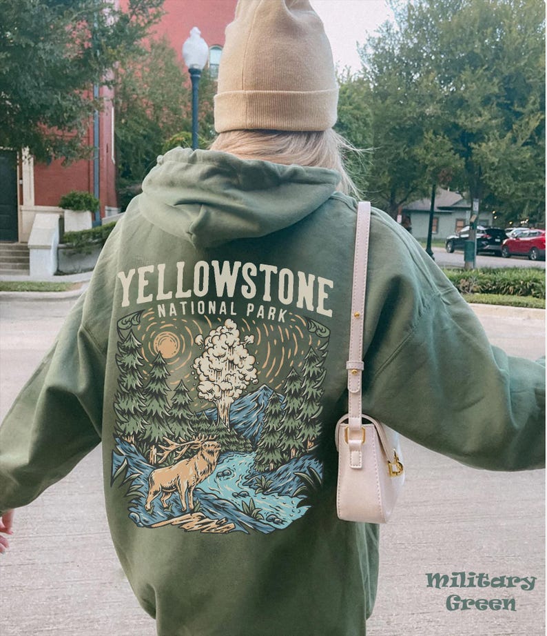 May include: A green hooded sweatshirt with a graphic print of a forest scene with a deer, a river, and a geyser. The text "Yellowstone National Park" is printed on the front of the sweatshirt.