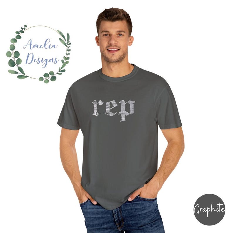 以下が含まれることがあります： グレーのTシャツに、白いかすれたフォントで「rep」とプリントされています。