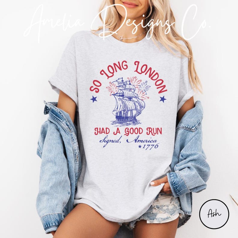 May include: Ash-colored t-shirt with a patriotic design. The graphic features a ship with fireworks, the text "SO LONG LONDON" and "HAD A GOOD RUN Signed, America *1776". The shirt is a casual wear item.