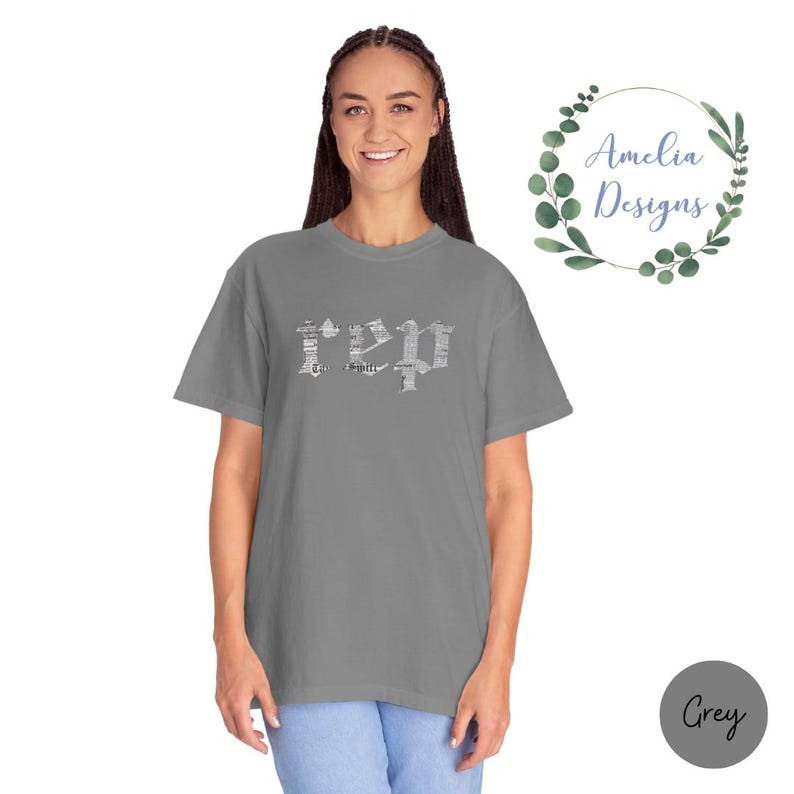 以下が含まれることがあります： 前面に白い「REP」という文字がプリントされたグレーのTシャツ。文字は新聞の印刷パターンで構成されています。