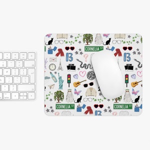 Op de afbeelding: Een witte muismat met een herhalend patroon van verschillende pictogrammen en tekst, waaronder "13", "Cornelia St" en een geest. De pictogrammen zijn in verschillende kleuren, waaronder rood, blauw, groen en zwart.