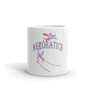 May include: White ceramic mug with a blue and red graphic of airplanes performing aerobatics. The text "AEROBATICS" is printed in blue on the mug.