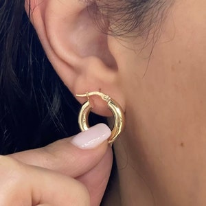 May include: A pair of gold hoop earrings. The earrings are simple and classic, with a smooth, polished finish.