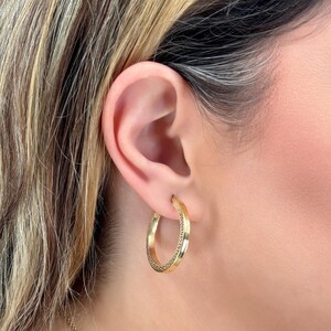 Stylish and stunning 14k yellow gold round hoops featuring a textured appearance and square tubular shape. These shiny ITALIAN gold hollow tubular earrings are lightweight and secure. Greek Key pattern Meandros trimmed square tubular hoop earrings.