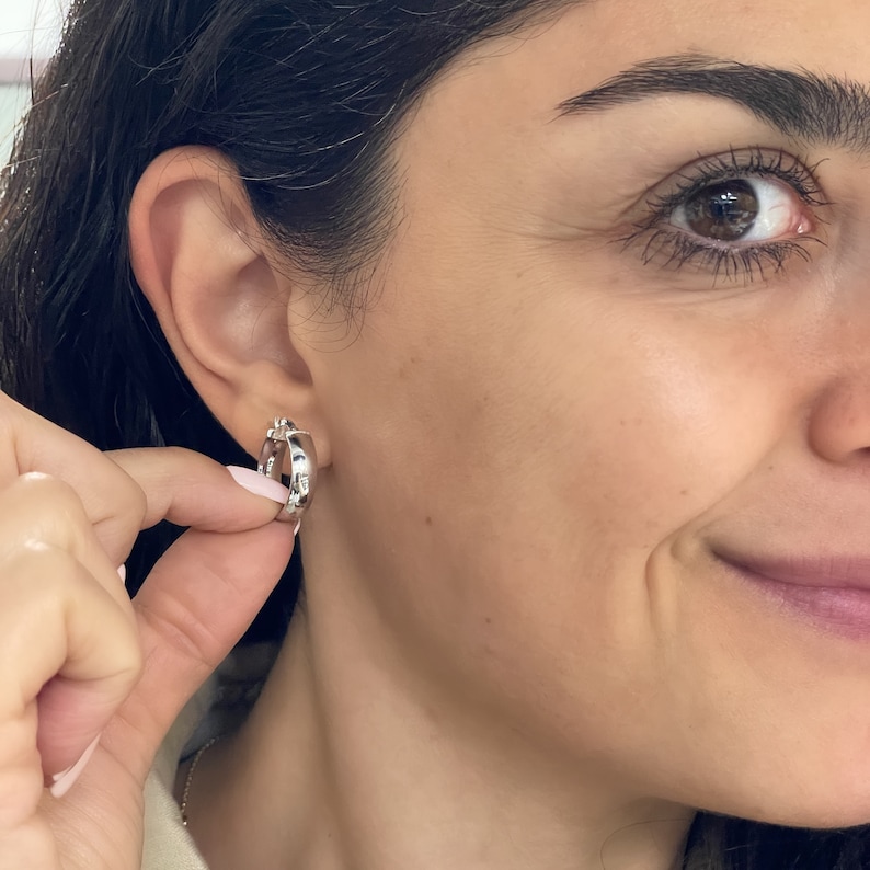 These super-chic and shiny 14k white gold flat, slightly chunky and wide hoops feature a domed tubular shape. These fine quality ITALIAN gold small/medium hoop earrings keep secure with click-top posts. Hollow lightweight classic white gold hoops.