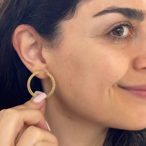 Stylish and stunning 14k yellow gold round hoops featuring a textured appearance and square tubular shape. These shiny ITALIAN gold hollow tubular earrings are lightweight and secure. Greek Key pattern Meandros trimmed square tubular hoop earrings.