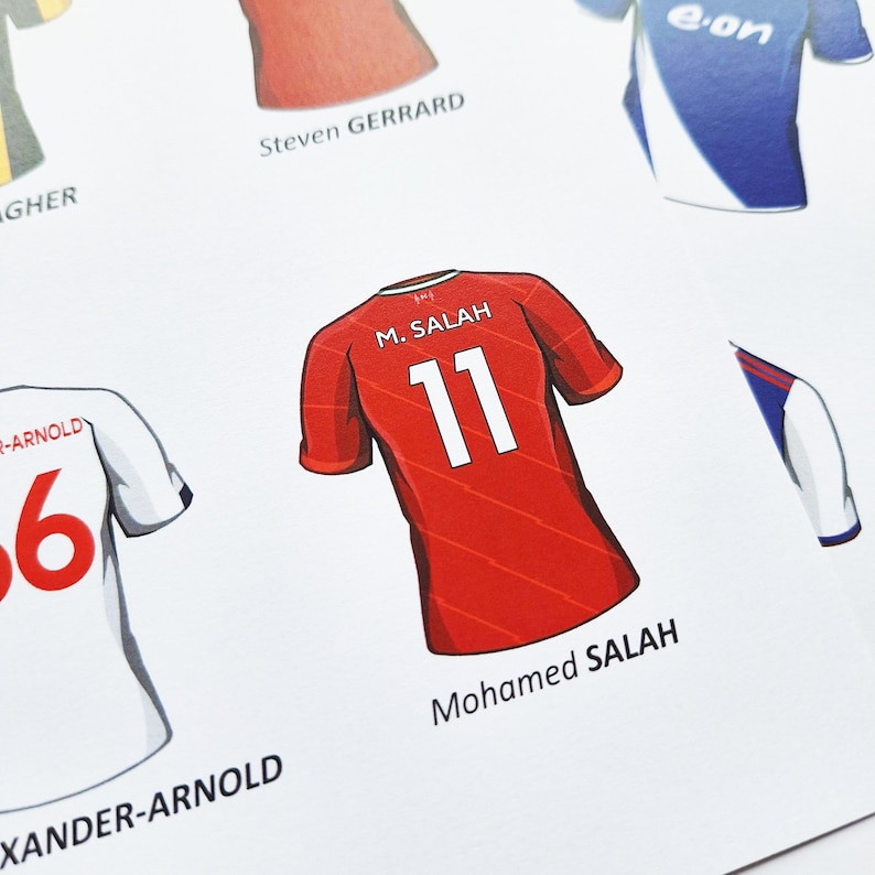 May include: A red football shirt with the number 11 on the back. The name "M. SALAH" is above the number and "Mohamed SALAH" is below the number.