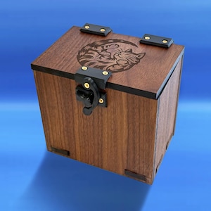 Peut inclure: Coffret en bois carré de couleur marron foncé avec des bordures noires et un fermoir noir. Le couvercle présente un motif gravé d'un chat dans un croissant. Le coffret est en bois et a un motif décoratif de chat.