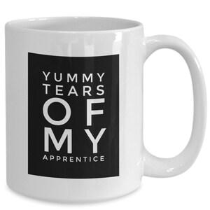 May include: White ceramic coffee mug with a black square design that says "Yummy Tears Of My Apprentice".