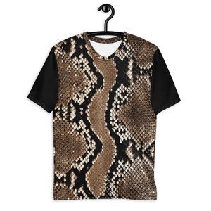 May include: A short-sleeved t-shirt with a snakeskin pattern on the front and back, and solid black sleeves. The snakeskin design features shades of brown, tan, and black, creating a realistic texture. The shirt is hanging on a black hanger.