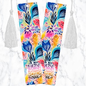 May include: Two colorful floral bookmarks with white tassels. The bookmarks feature the text "I'm not lazy, I'm energy saving mode".