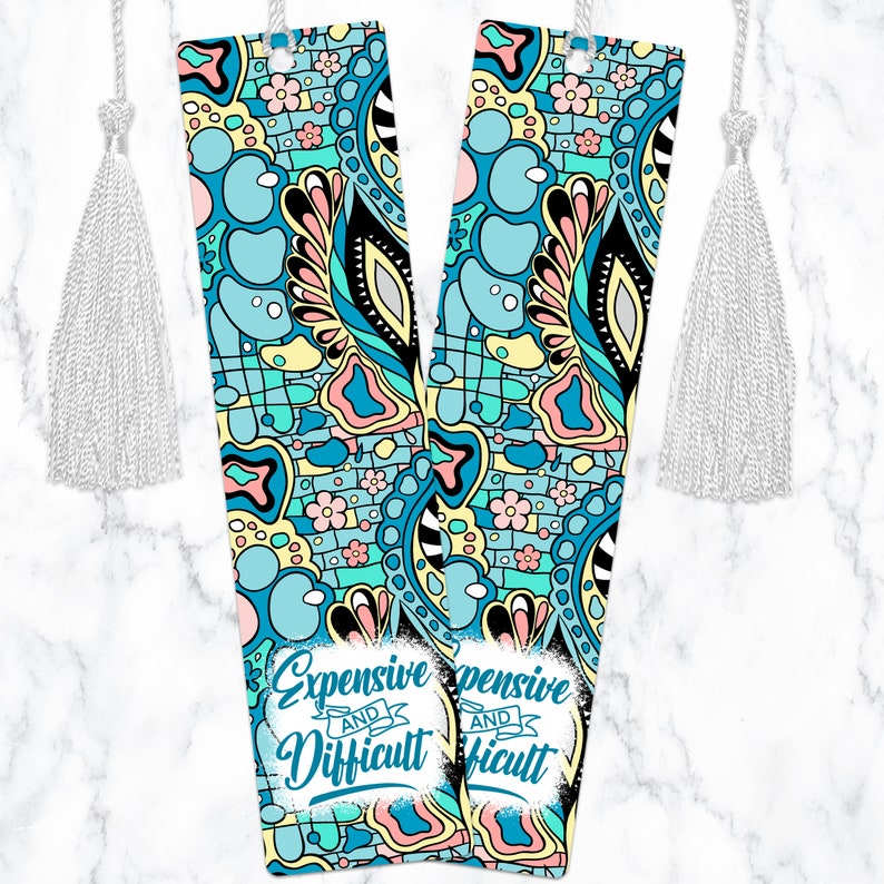 May include: Two colorful bookmarks with a blue, yellow, pink, and green abstract pattern. The bookmarks have a white tassel and the text "Expensive and Difficult" on them.