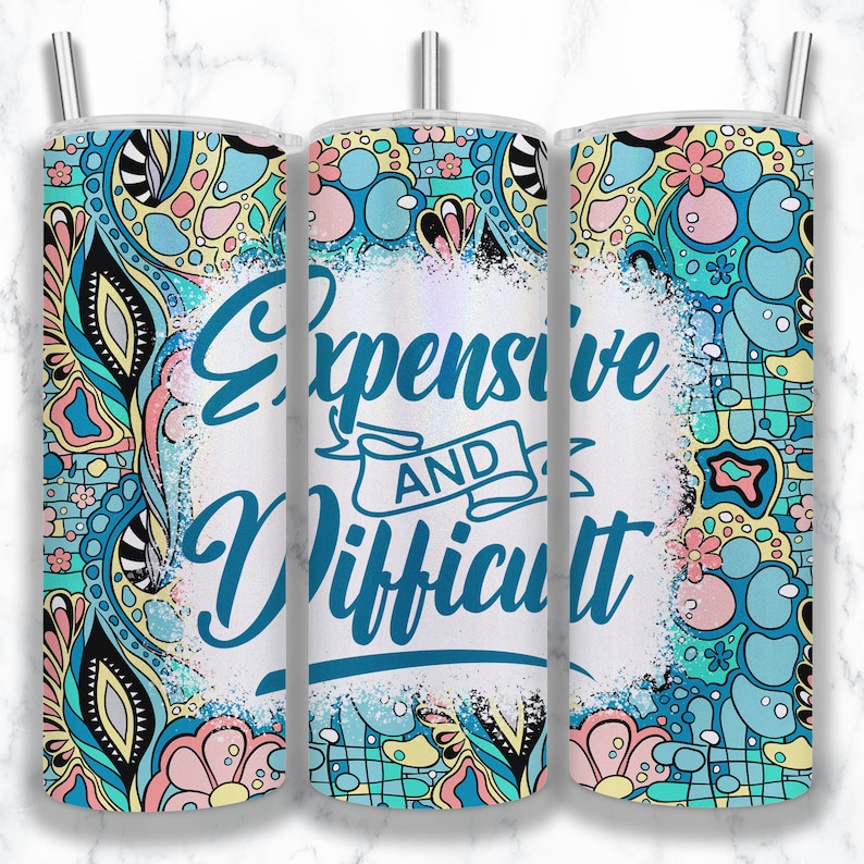 May include: A white tumbler with a blue and green floral pattern and the text "Expensive and Difficult" in blue lettering.