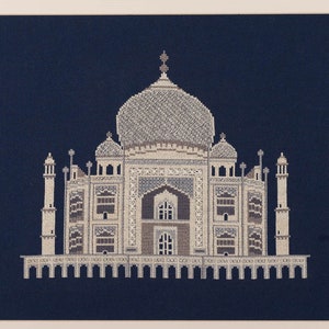 May include: A white cross-stitch embroidery of the Taj Mahal, a famous mausoleum in India, against a dark blue background.