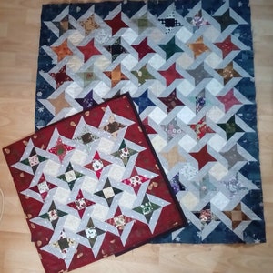 May include: Two patchwork quilts with a star pattern. The larger quilt is blue with white stars and the smaller quilt is red with white stars.