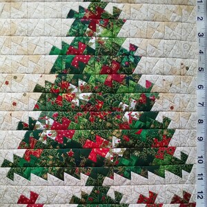 K&ouml;nnte beinhalten: Ein handgefertigter Weihnachtsbaum-Patchworkblock mit einem Patchwork-Design aus gr&uuml;nem, rotem und goldenem Stoff. Der Block besteht aus kleinen Quadraten und Dreiecken und bildet ein festliches und komplexes Muster.