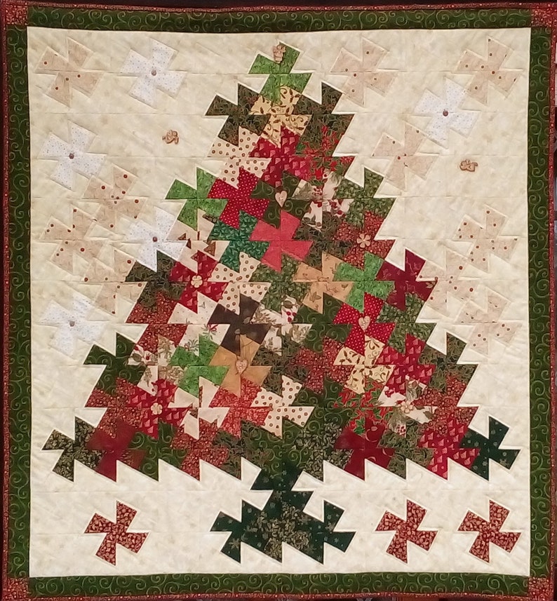K&ouml;nnte beinhalten: Ein gesteppter Weihnachtsbaum-Wandbehang mit wei&szlig;em Hintergrund und einem Patchwork-Design in Gr&uuml;n, Rot und Braun.