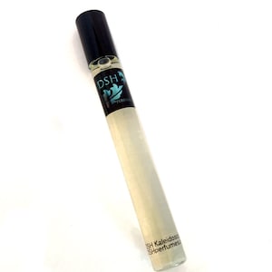 Puede incluir: Una botella de vidrio transparente con una tapa negra y una etiqueta que dice "DSH Perfumes" y "DSH Kaleidoscope".