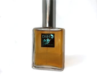 Può includere: Un flacone di profumo rettangolare in vetro riempito con liquido color ambra. Il flacone presenta un tappo cilindrico argentato e un'etichetta nera quadrata sul davanti con il testo DSH in lettere bianche sopra un disegno grafico di una foglia verde acqua.