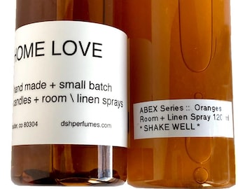 Może przedstawiać: Dwie bursztynowe butelki szklane z białymi etykietami. Butelka po lewej stronie ma napis "HOME LOVE" i informacje o produkcie. Butelka po prawej stronie ma napis "ABEX Series:: Oranges Room + Linen Spray 120 ml * SHAKE WELL *"