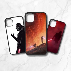 May include: Three different phone cases featuring Star Wars characters. The first case is white with a black silhouette of Darth Vader. The second case is orange with a scene from Star Wars. The third case is red with a silhouette of a character from Star Wars.