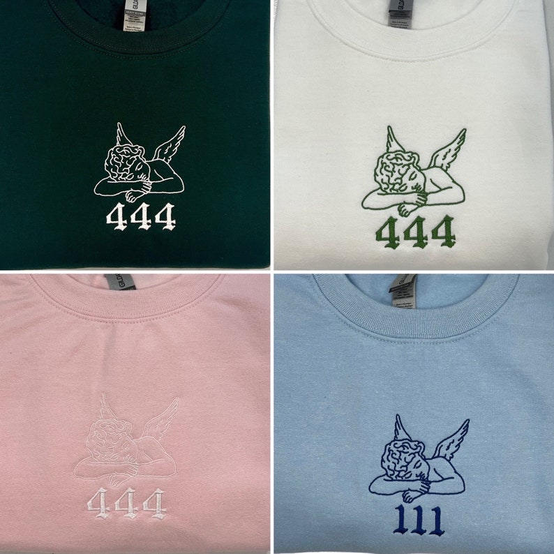 May include: Four sweatshirts in different colors: dark green, white, pink, and light blue. Each sweatshirt features an embroidered design of an angel with the number "444" or "111" below. The angel and numbers are in contrasting colors.