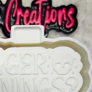 May include: White silicone mold for making resin crafts. The mold is shaped like a banner with the text "Trigger Warnings? Count me in."