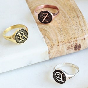 Peut inclure: Trois bagues signet avec des lettres initiales différentes. Les bagues sont en or, or rose et argent. Les lettres sont en police gothique.