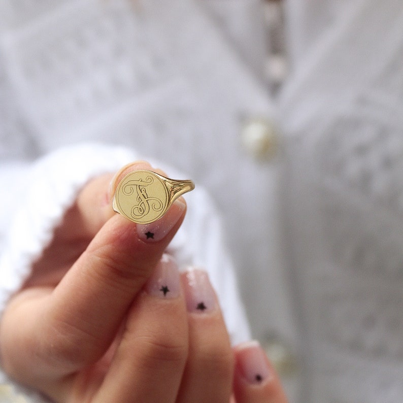 May include: A gold signet ring with a cursive letter "T" engraved on the face.
