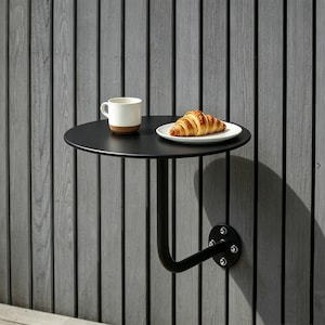 Könnte beinhalten: Eine weiße Keramik-Tasse mit schwarzem Henkel und dem Text "But First, Coffee" in schwarzer, handschriftlicher Schrift. Die Tasse steht auf einer weißen Oberfläche.