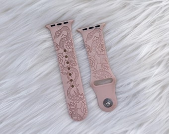 May include: Two pink silicone Apple Watch bands with a floral and snake design. The bands have a moon and stars pattern.
