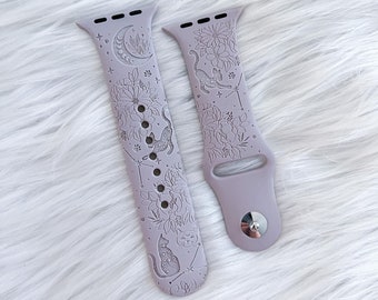 May include: A pair of light purple silicone watch bands with a floral and cat design. The bands are designed for Apple Watches.