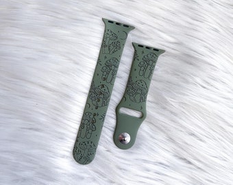May include: Two green Apple Watch bands with a mushroom and moon design. The bands are made of silicone and have a smooth finish.