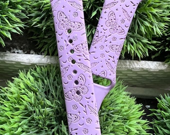 May include: A lavender Apple Watch band with a butterfly and moon pattern.