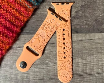May include: A peach-colored Apple Watch band with a game-themed design. The band features a variety of graphics, including controllers, game characters, and the words "Game Over".