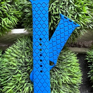 May include: A bright blue Apple Watch band with a geometric pattern. The band is made of silicone and has a smooth, comfortable feel.