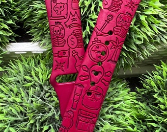 May include: Red watch band with a pirate theme. The band features engraved images of a treasure map, skull and crossbones, coins, an anchor, a compass, and a pirate captain. The band is made of a flexible material.
