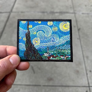 May include: An embroidered patch featuring a recreation of Vincent van Gogh's "Starry Night" painting. The patch is black with a blue, yellow, and green embroidered image.