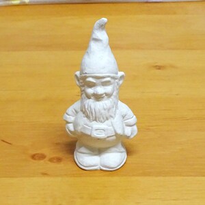 May include: White ceramic garden gnome figurine with a pointed hat, a beard, and a belt.