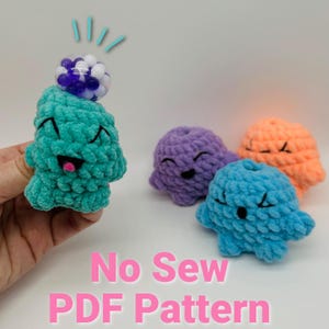 May include: A crochet pattern for making no-sew plush toys. The pattern includes four different color options: teal, purple, blue, and orange. Each plush toy has a cute, smiling face.