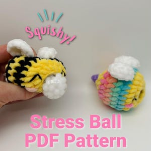 May include: Two crocheted stress balls shaped like bees. One bee is yellow and black with white wings. The other bee is rainbow colored with white wings. Both bees have a clear plastic bubble filled with white beads.