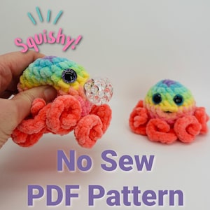 Peut inclure: Deux peluches de poulpe en crochet de couleur arc-en-ciel avec des yeux globuleux. Le poulpe de gauche tient une perle en plastique transparente. Le texte "No Sew PDF Pattern" est écrit sous les peluches.