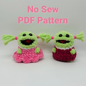 May include: Two crocheted green plush toys with pink and burgundy dresses. The toys have black eyes, red mouths, and green yarn hair. The text "No Sew PDF Pattern" is above the toys.