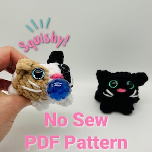 May include: A crochet pattern for a no-sew, squishy cat toy. The pattern includes two cats, one with brown, white, and black fur and the other with black fur. Both cats have green eyes and pink noses. The text "Squishy!" is written in pink letters above the cats. The text "No Sew PDF Pattern" is written in pink letters below the cats.
