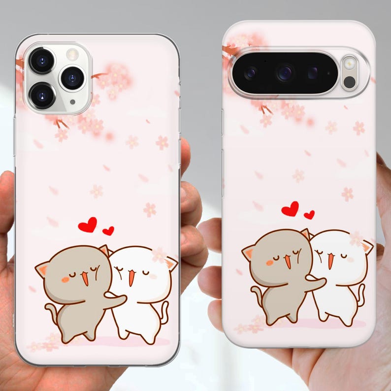 May include: Two phone cases with a pink background and a cartoon cat design. One case is for an iPhone, the other for a Google Pixel. The design features two hugging cats with hearts above them and cherry blossom accents.
